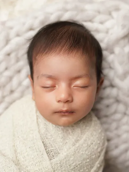 A simple, classic portrait of a sleeping newborn's face. The clean composition and soft lighting highlight the perfection of their features.