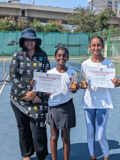 Trisha and Rumi with a family member and their certificates after their doubles victory.