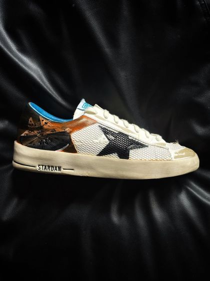 A pair of luxury Golden Goose sneakers with a custom-painted space and cloud theme.