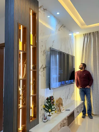 Admiring the completed TV unit design. The combination of a marble-finish back panel, a fluted wood partition, and integrated display shelves creates a luxurious focal point.