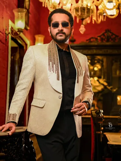 Actor Parambrata Chattopadhyay in a stylish blazer for an Anandalok magazine cover shoot. The opulent, red-walled interior adds a touch of classic luxury to this modern menswear portrait.
