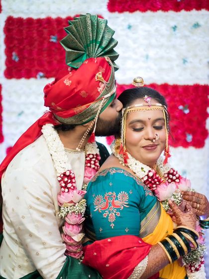 A sweet forehead kiss, a classic romantic pose against a beautiful floral backdrop.