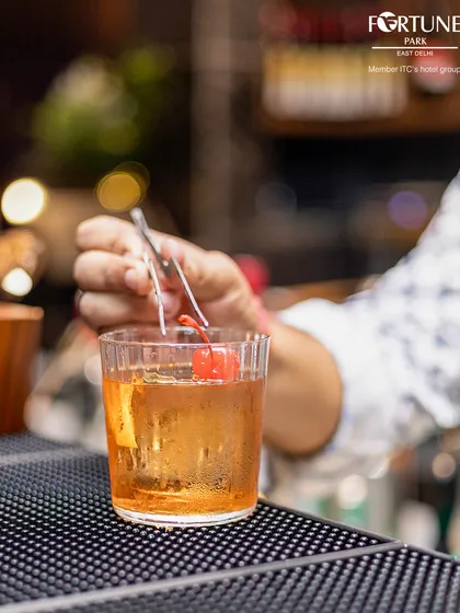 A classic Old Fashioned being prepared with care, complete with a cherry garnish. A timeless choice for a sophisticated evening.