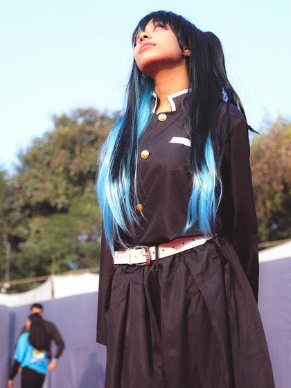 A full-costume shot of the Muichiro cosplayer, capturing the character's thoughtful pose against an outdoor backdrop. We adapt to different lighting conditions, from indoor halls to outdoor venues, to get the perfect shot.