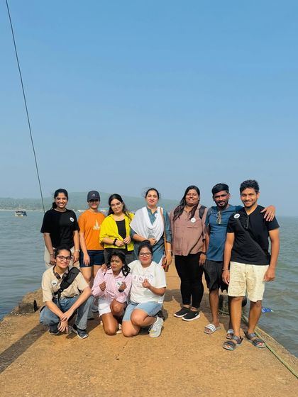 A group of travelers posing on a pier in Gokarna, with the sea stretching out behind them.