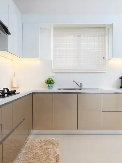 Natural light from the window enhances the brightness of this kitchen. The clean lines of the cabinetry and the simple, elegant color palette create a space that feels both modern and timelessly serene.