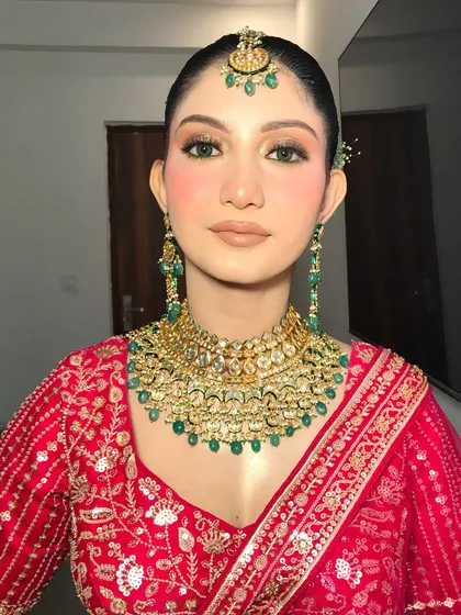 A frontal view of the bride's jewelry. The intricate details of the gold and emerald kundan necklace are the centerpiece of her look.