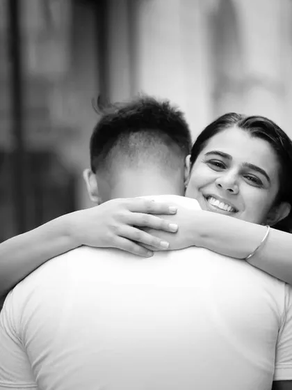 A hug is a simple gesture full of meaning. This candid, over-the-shoulder shot captures the bride-to-be's joyful smile, showing a moment of pure happiness and comfort during their pre-wedding shoot.