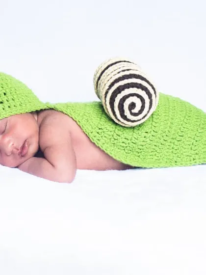 For a touch of fun, I offer adorable costume setups like this cute snail outfit. The crocheted costume is soft and comfortable for the baby, creating a playful and unique photograph.