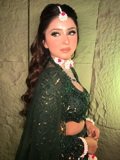 A side profile of the Mehendi look, showing off the soft waves in the hair and the intricate details of the floral maang tikka.