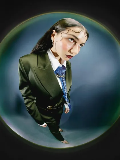 A fisheye portrait of a model in a tailored suit, subverting traditional corporate attire. The wide-angle distortion gives the formal wear an unconventional, playful twist.