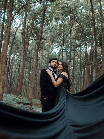 The dark fabric of our black trail gown creates a beautiful contrast with the forest setting. The flowing train adds a touch of mystery and romance to this pre-wedding photo.