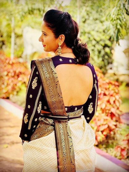 A side profile of our client wearing a deep purple, full-sleeve embroidered blouse with her off-white and gold Kanjeevaram saree.