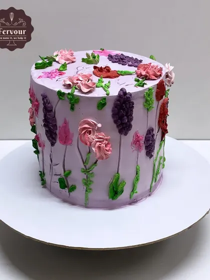 A chocolate mousse cake decorated with a garden of hand-piped flowers. The purple base colour makes the colourful flowers pop.
