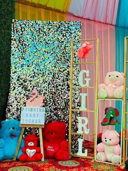 A gender reveal corner at a baby shower, decorated with colorful teddy bears and 'Girl' 'Boy' marquee letters.