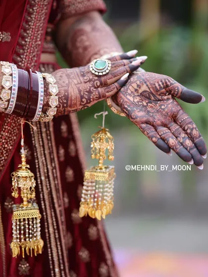 The deep henna stain beautifully complements the bride's red lehenga and golden kalire. This is the complete bridal look that every bride dreams of.