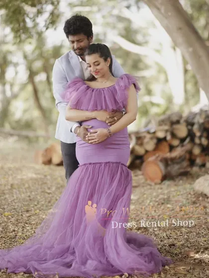 This lavender mermaid gown is perfect for romantic couple maternity photos. The fitted bodice and ruffled neckline create a flattering shape, while the soft tulle train adds a touch of elegance to this beautiful moment captured in a woodland setting.