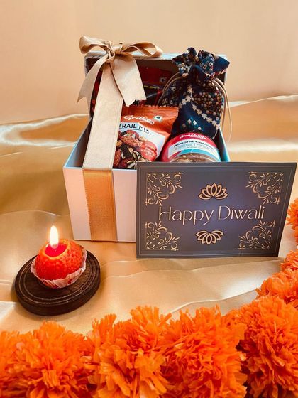 This striped gift box is filled with a delightful mix of trail mix, cookies, and a bandhani potli, tied with a beautiful ribbon for a perfect Diwali presentation.