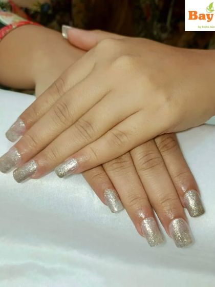 Elegance with a touch of shimmer. These long, square-tipped nails feature a beautiful silver glitter polish that is perfect for parties and special events.