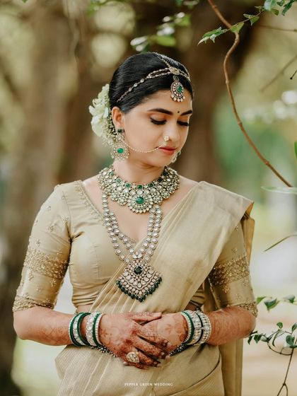 A serene and divine portrait of the bride in a golden saree, her eyes gently closed. This image captures a moment of quiet contemplation and grace on her wedding day.