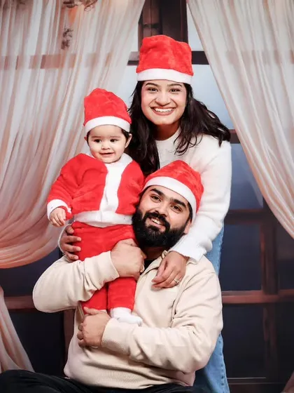 A joyful family photo, with the baby held up high by her smiling parents.