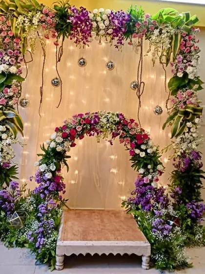This is a truly grand design for a home Ganpati or engagement, featuring a multi-layered floral arch and beautiful lighting.