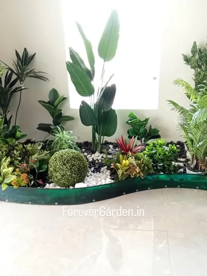 A custom-designed curved planter for a home interior, filled with a diverse mix of artificial plants, rocks, and a central moss ball. This unique piece is designed to fit perfectly in an unused corner.