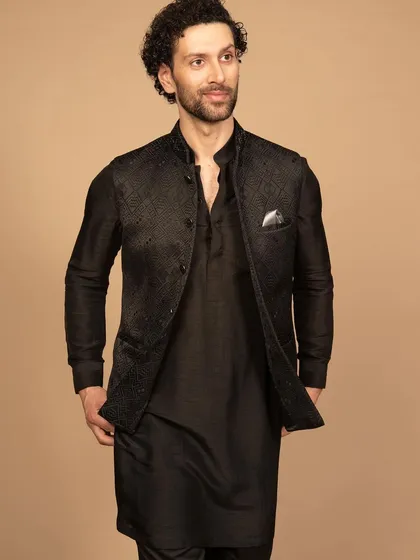A luxurious black Nehru jacket with subtle, tonal embroidery, layered over a matching black kurta. This all-black look is the definition of sleek, modern elegance, perfect for an evening reception or cocktail event.
