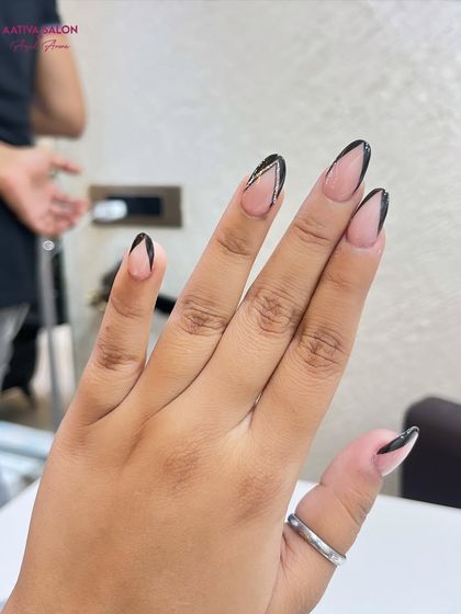 A modern and graphic take on the French manicure. This design uses sharp black lines to create a V-shape tip, accented with a hint of silver glitter.
