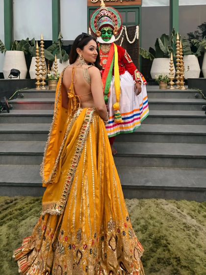 A vibrant yellow lehenga for an event in Ludhiana, posing with a traditional Kathakali dancer. I love when events celebrate the rich culture of India.