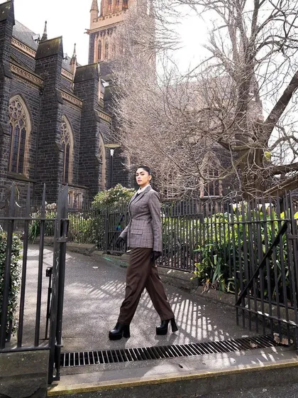A walking shot of the plaid suit, showing how it looks in motion against an architectural backdrop.