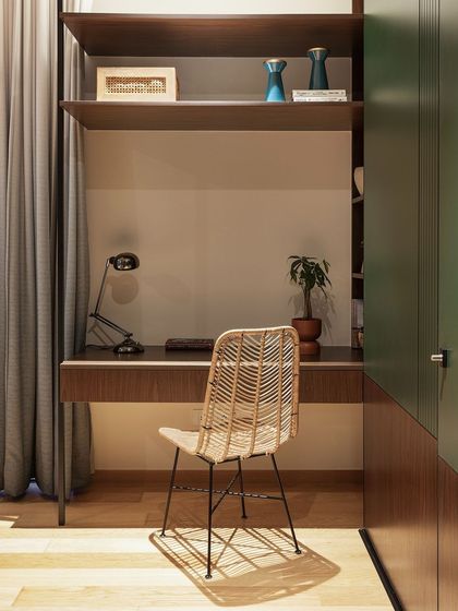 This compact study nook is cleverly built into a wardrobe unit. The dark wood desk and shelving, paired with a cane chair, create a cozy and efficient workspace.