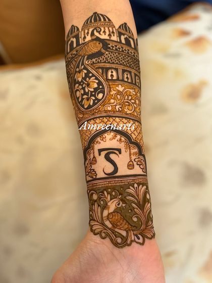 An arm design featuring a majestic peacock perched atop a palace dome, with the initial 'S' below.