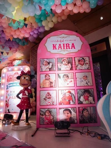 A personalized photo display for the birthday girl's "One-derful Year," set next to a Minnie Mouse prop and a welcome sign.