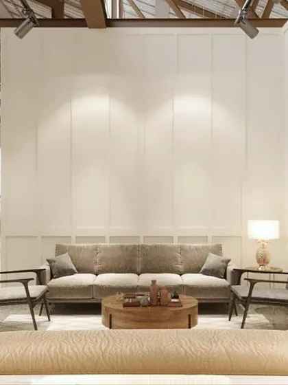 A living room setting that showcases a complete furniture collection. The high, exposed-beam ceiling of the original mill building is contrasted with soft, neutral furnishings and warm accent lighting.