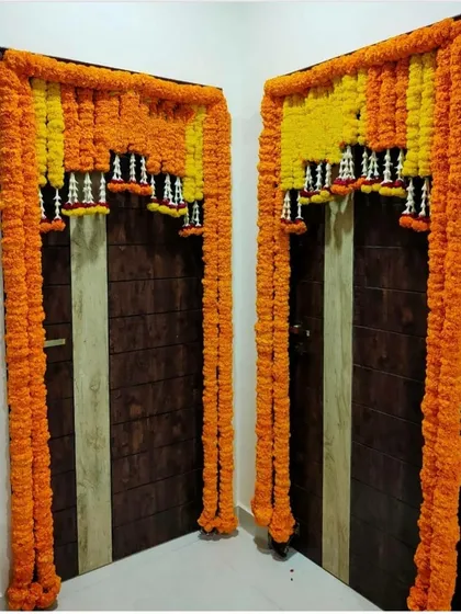 A classic door decoration using thick garlands of orange and yellow marigolds. This is a popular and auspicious design for festivals, pujas, and weddings, and we can install it quickly.