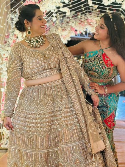 Our client sharing a happy moment with her daughter, both looking lovely. She is wearing our heavily embellished beige lehenga, a perfect choice for a family wedding.