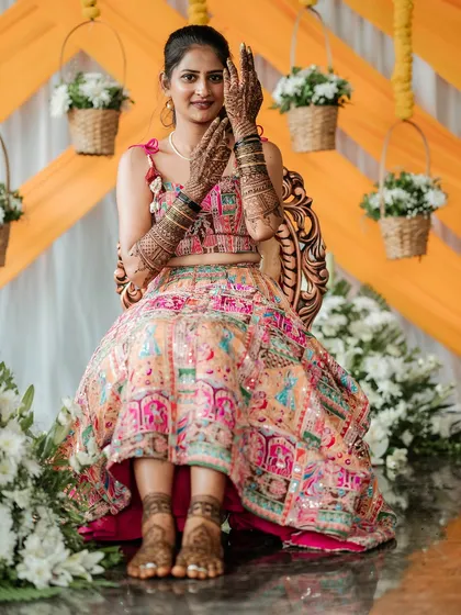 For Chethana's mehendi ceremony, I created this vibrant and playful lehenga. The skirt features colorful patchwork embroidery, and the blouse is designed with a modern tie-up back and charming tassels.