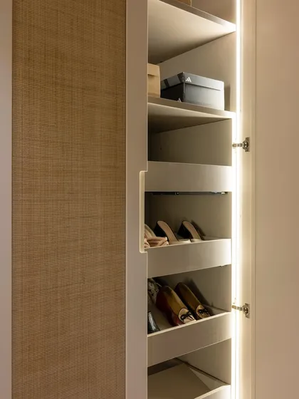 Another view of the custom shoe storage, with angled shelves and soft lighting. This solution transforms shoe storage from a cluttered mess into a clean, elegant display.