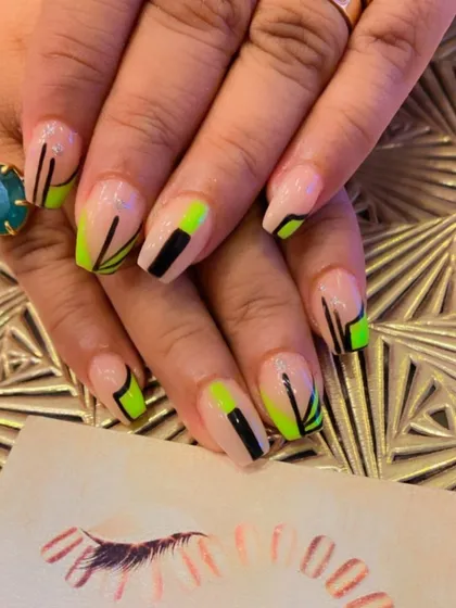 A bold, geometric design on coffin-shaped nails. The sheer nude base is decorated with sharp lines and color blocks in neon green and black.