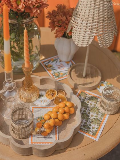A close-up of a tabletop styled with dried oranges, custom stationery, and a wicker lamp, adding texture and detail.
