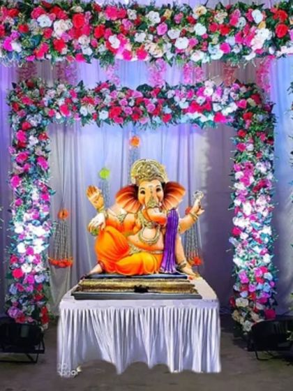 For a very lush and full floral look, we can create a complete arch and ceiling decoration packed with multicolored flowers. This design uses dense arrangements of pink, red, and white flowers for a truly grand floral mandap.