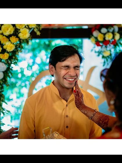 A candid shot of the groom wincing with a smile as Haldi is applied, a classic and funny moment from the ceremony.