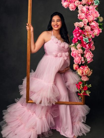 A joyful portrait in our pink ruffled gown, using a floral-adorned frame as a creative prop for a fun and beautiful shot.