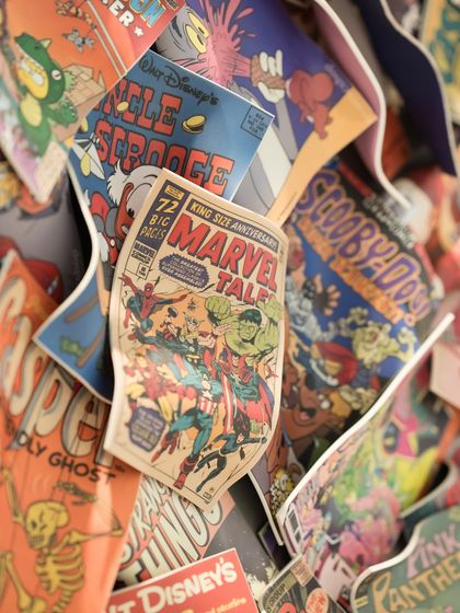 A close-up of the "Comic Confluence" installation, showing classic Marvel and Disney comic book covers layered together in a dynamic collage.