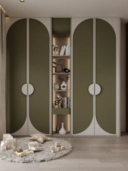 This custom wardrobe design for a kids' room features playful arched doors in an olive green and white finish, with a central open shelf for displaying favorite toys and books.