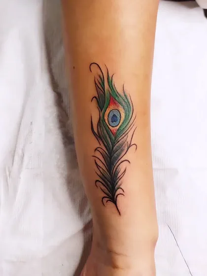 A vibrant peacock feather design was used to completely cover an old name tattoo on the forearm. The rich greens and blues, combined with fine-line details, make for a beautiful and effective cover-up that gives the client a fresh start.