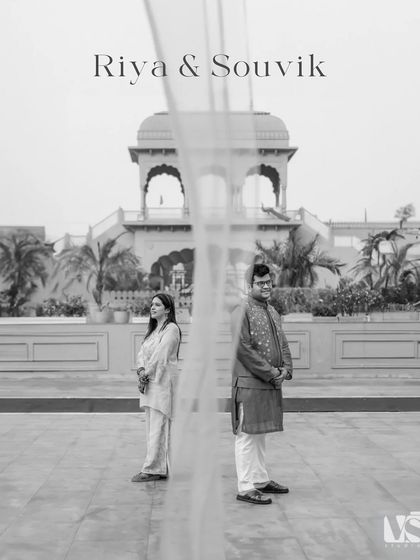 A beautifully composed black and white portrait, with a sheer curtain creating a soft, ethereal separation between the couple. This artistic shot is both modern and timeless.