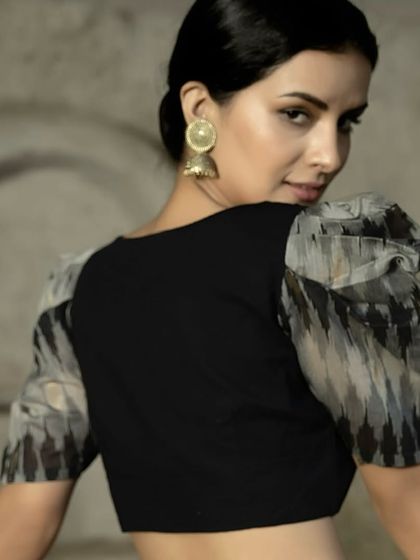 A back view of the black puff sleeve blouse. The simple, clean back puts all the focus on the dramatic sleeves and the overall silhouette, creating a look of effortless style.