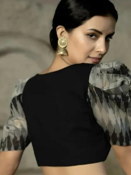 A back view of the black puff sleeve blouse. The simple, clean back puts all the focus on the dramatic sleeves and the overall silhouette, creating a look of effortless style.